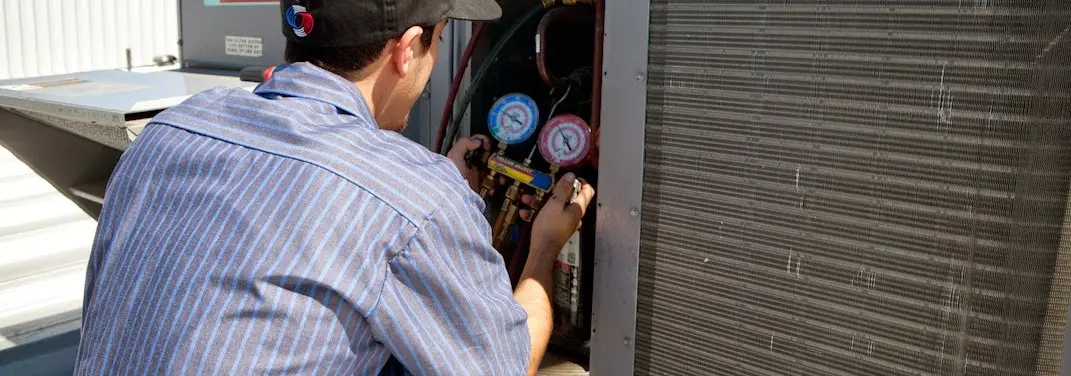 HVAC technician servicing a condenser unit in Clementon